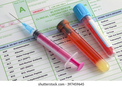 Blood Vials And Syringe With Needle On Top Of Lab Results.