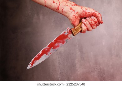 Blood Woman's Hand Holding Bloody Knife On A Gray Background. The Concept Of Violence, Murder