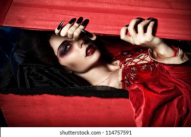 Bloodthirsty female vampire rises from the coffin on the night cemetery.