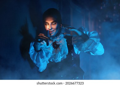 A bloodthirsty vampire aristocrat standing in the castle and looks at a candle in his hands in darkness. 19th century style. Halloween.