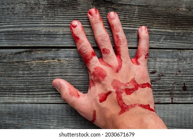 A Bloody Man's Hand On The Background Of A Gray Wooden Table. The Concept Of Injury Trauma At Work. Labor Protection.