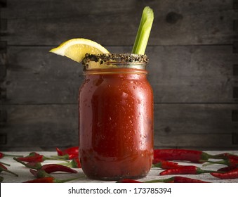 Bloody Mary or Bloody Ceasar with celery in mason jar rimmed with black pepper
