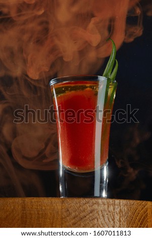 Bloody Mary cocktail, decorated with greenery, in a surreal landscape in dark colors close-up.