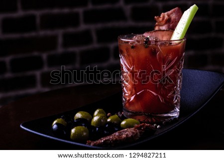 Bloody mary cocktail garnished with celery sticks, bacon and olives.