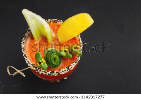 Bloody Mary cocktail with green olive, lettuce and lemon on black table, closeup