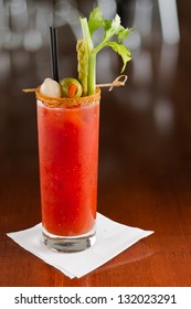 bloody mary cocktail isolated on a busy bar top garnished with onions, olives, asparagus and celery