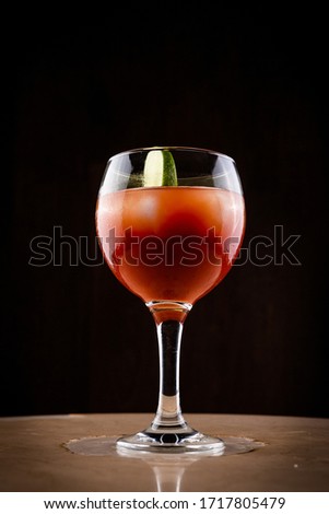 Bloody mary cocktail with lime and ice in wide glass with dark background. Classic cocktail with black background on marble table. General shot.
