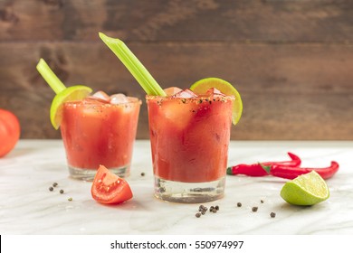 Bloody Mary cocktails with red hot chili peppers, slices of lime, celery sticks, a piece of tomato and copyspace