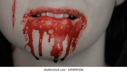 Bloody mouth and teeth of girl. Vampire woman Halloween makeup with dripping blood. Friday 13th theme