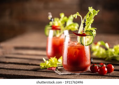 Bloody or virgin mary cocktail served in a cup with celery sticks and cherry tomatoes.