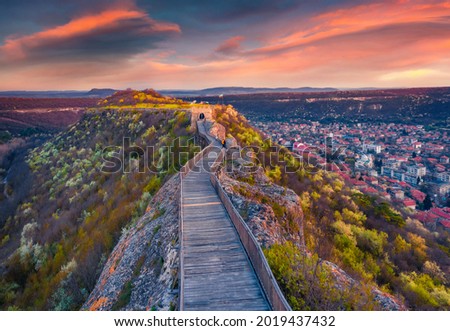 Blooming cherry trees on the hills of old fortress. Aerial spring cityscape of Provadia town, located in a deep karst gorge along the Provadiya River. Exciting sunset in Bulgaria, Europe.