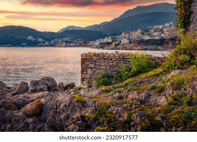Blooming flowers on the shore of Adriatic sea in Himare town. Amazing sunset in Albania, Europe. Traveling concept background.