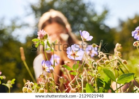 Blooming flowers in spring and child with hay fever blowing nose in background