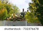 A blooming hydrangea bush with a partial view of the Hildene mansion in the background. Fall foliage is present.