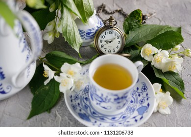 Blossoming tender jasmine flowers and a tea set with a mechanical clock on a chain.