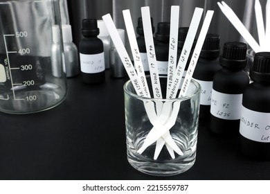 blotter papers are in a glass with background essential oil and frangrance oil bottle for testing smell during blending process for choosing nice scent for scented candles and body perfume in lab - Shutterstock ID 2215559787