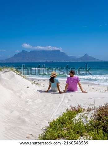 Bloubergstrand Cape Town South Africa on a bright summer day, Blouberg beach, withe powder sand and blue ocean. couple on the beach, men and woman chilling on the beach