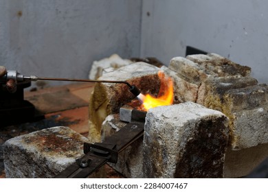 A blow torch is used to apply heat to a crucible full of silver to be melted down - Powered by Shutterstock