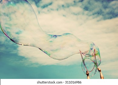 Blowing big soap bubbles in the air. Vintage freedom, summer concepts. Puffy clouds sky.