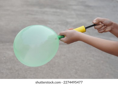 Blowing green balloon by hand air pump, inflates  air to balloon Concept, children play, toy and equipment to play fun games or prepare party.                         