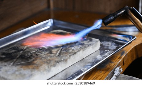 Blowtorch is heating metal to make a jewel in a workshop - Powered by Shutterstock