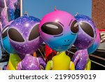 Blowup inflatable alien toys with big heads and large eyes at a fair.