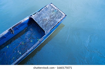 Blue Abandoned Row Boat, Vintage Blue Boat Sinking With Leaves Inside, Damaged And Left To Rot Rowing Boat By The Bridge