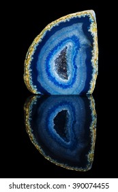 Blue agate geode on a black reflective surface.