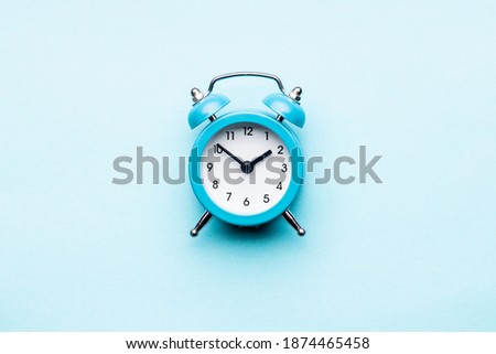 blue alarm clock flat lay over blue background. above view. time minimal concept. outer space.