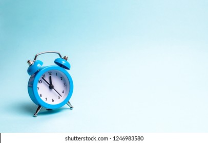 A blue alarm clock on a light blue background. The concept of waiting for a meeting, a date. Punctuality. The cost of hourly work of a specialist, business planning. Discussing cases. - Shutterstock ID 1246983580
