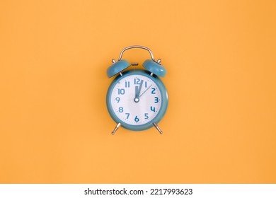 Blue alarm clock on orange background isolated, flat lay.