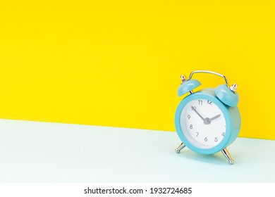 Blue Alarm Clock Over Yellow Background. Studio Shot. Time Concept. Template For Design.