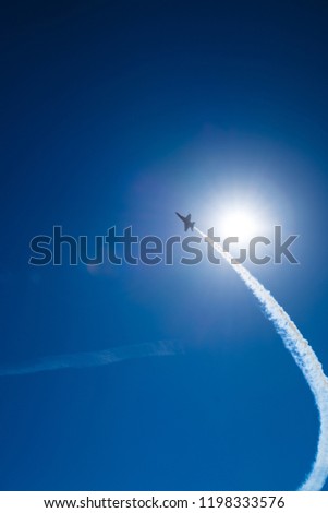 Blue angels flying around in the sky in San Francisco near the Golden gate bridge with blue sky and smoke trail as it flies by the sun