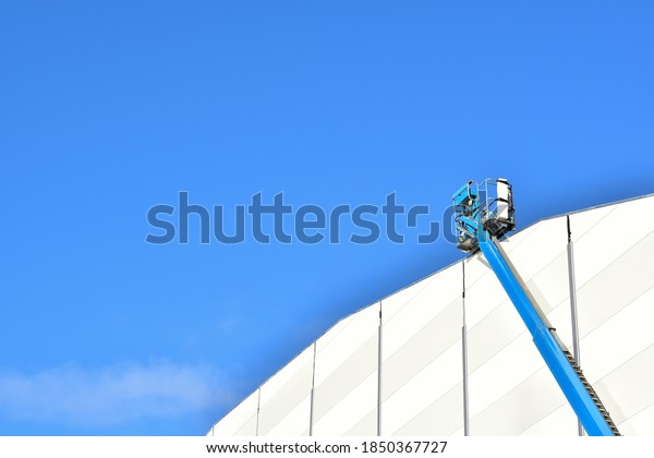 Blue\
articulate boom lift or telescopic boom lifts and bucket crane\
mounted on truck to safety for working at heights and articulating\
boom lift reaching high up again the nice blue sky.\
