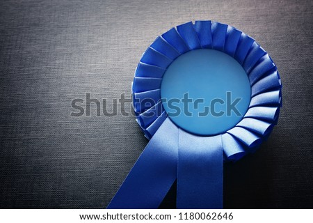 Blue award rosette with ribbons and copy space on black background