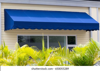 Blue Awning Over White Aluminium Frame Window Of Shop