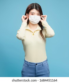 In The Blue Background. Asian Beauty With Mask

