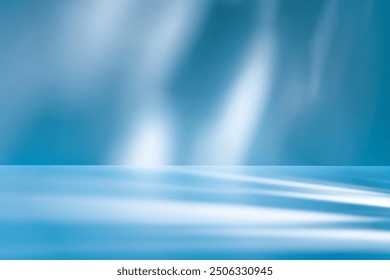 Blue background with smooth light reflections and shadows on wall and table. Mock up with blurry spotlights for winter presentation, branding products, cosmetics and food.