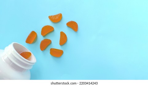 Blue Background With Vitamin C Gummies In The Form Of Orange Slices. Space For Text