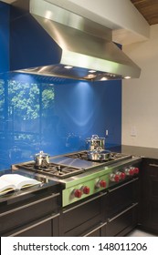 Blue Backsplash And Stainless Steel Vent Hood In Modern Kitchen