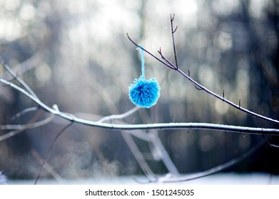 Blue Ball Of Yarn Pompom Hanging On A Bare Branch On A Frosty Day