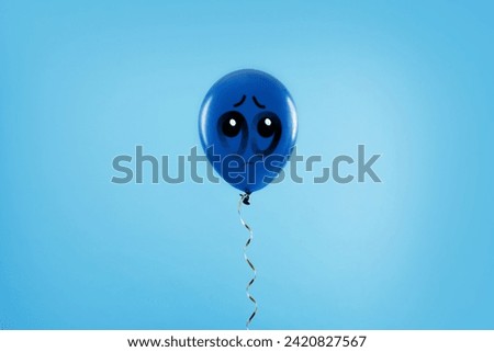 Blue balloon with sad face on light blue background