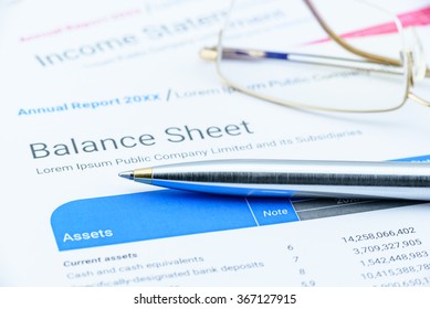 Blue Ballpoint Pen On A Corporate Balance Sheet With Eye Glasses Waiting For An Auditor To Audit Before Passing To Executive Committee In The Boardroom. Financial And Investment Analysis Concept.