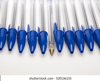 Blue ballpoint pens capped with one uncapped on white background