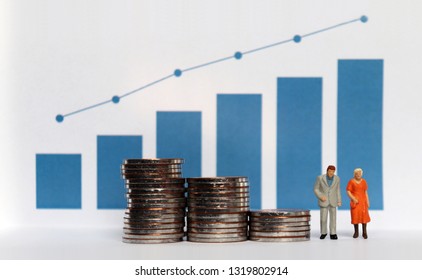 Blue Bar Graph With Flow Linear Graph. The Stack Of Coins And Miniature Older People. Concepts About Increasing Life Expectancy And The Lack Of Retirement Funds.