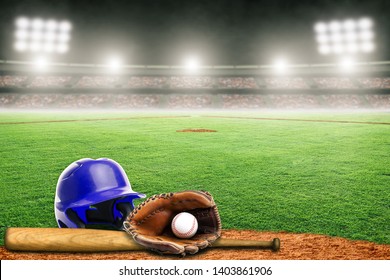 Blue Baseball Helmet, Bat, Glove And Ball On Field At Brightly Lit Outdoor Stadium. Focus On Foreground And Shallow Depth Of Field On Background And Copy Space.