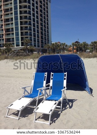 Blue beach chairs and sun / wind tent waiting for you.