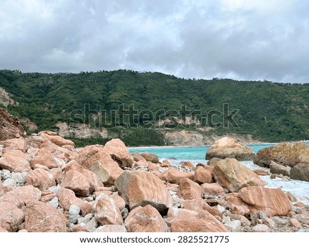 A blue beach set against a backdrop of green hills and pink rock formations—a sight that’s a true feast for the eyes—offers a place to take a brief break from the exhausting daily grind.