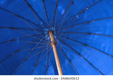 Blue beach umbrella in low angle view. Summer vacation. Shade under parasol. - Powered by Shutterstock