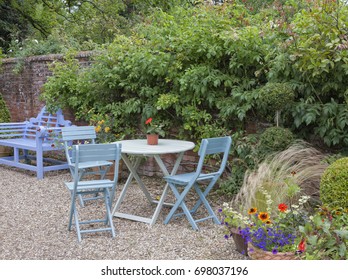 Blue Bench, Patio Table And Chairs By A Wall In An English Cottage Garden, Summertime .